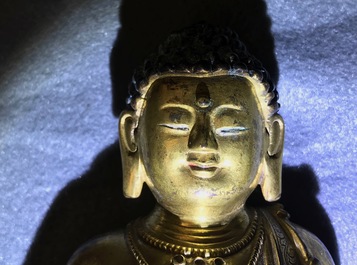 Een Chinese verguld bronzen figuur van een staande Boeddha met inscriptie, Qianlong