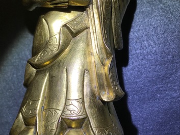 Een Chinese verguld bronzen figuur van een staande Boeddha met inscriptie, Qianlong