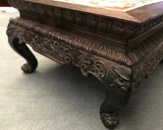 A Chinese carved wooden stand with famille rose plaque, 19th C.