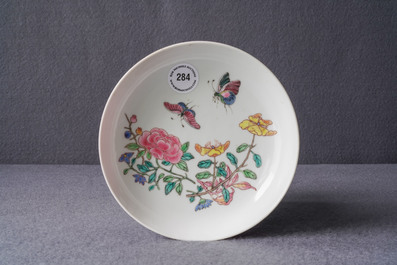 A Chinese famille rose 'ruby back' saucer dish with butterflies among flowers, Yongzheng