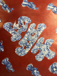 Une plaque laqu&eacute;e rouge incrust&eacute;e de porcelaine de Chine en bleu et blanc, 19/20&egrave;me