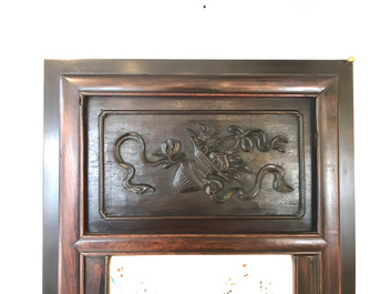 Une armoire en bois sculpt&eacute; orn&eacute;e de 23 plaques en porcelaine de Chine qianjiang cai, 19/20&egrave;me