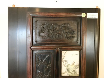 Une armoire en bois sculpt&eacute; orn&eacute;e de 23 plaques en porcelaine de Chine qianjiang cai, 19/20&egrave;me