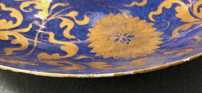 Een Chinese poederblauwe en vergulde schotel met floraal decor, Kangxi