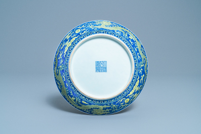 Un plat en porcelaine de Chine en bleu et jaune &agrave; d&eacute;cor d'un dragon, marque et &eacute;poque de Qianlong