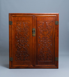 A Chinese wooden two-door cupboard with carved floral panels, 19th C.