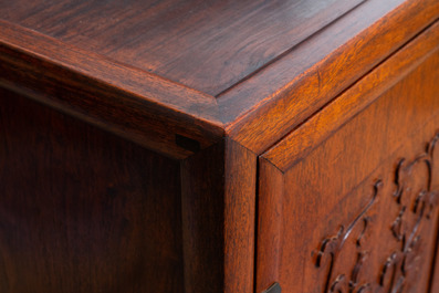 A Chinese wooden two-door cupboard with carved floral panels, 19th C.