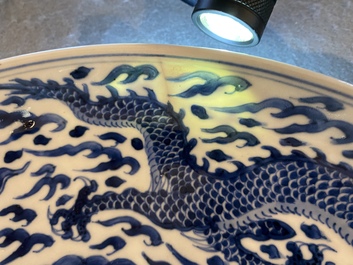 Un plat en porcelaine de Chine en bleu et blanc &agrave; d&eacute;cor d'un dragon, marque et &eacute;poque de Kangxi