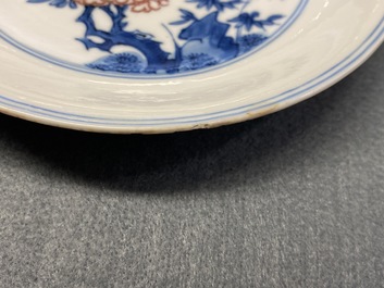 A Chinese blue, white and copper red saucer dish with floral design, Kangxi