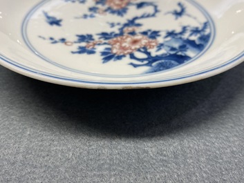 A Chinese blue, white and copper red saucer dish with floral design, Kangxi