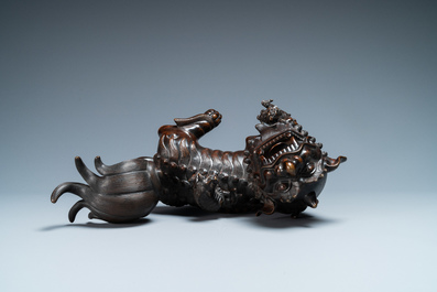 A Chinese bronze model of a Buddhist lion on a finely carved wooden stand, 18th C.