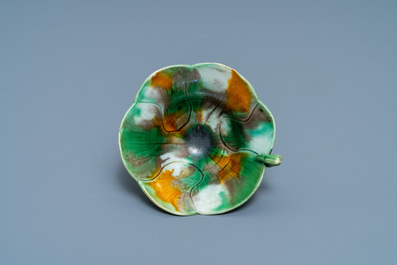 A Chinese 'egg and spinach'-glazed lotus cup and saucer with applied design, Kangxi