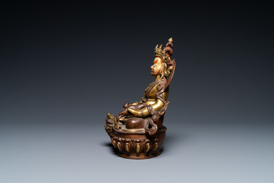 A Sino-Tibetan partly gilt bronze figure of Jambhala with inscriptions on the back, 19th C.