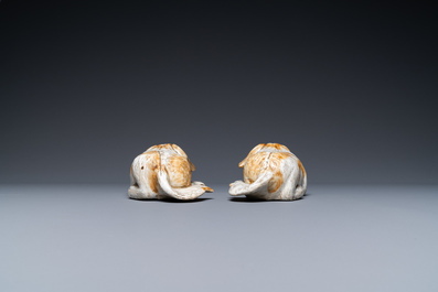 A pair of Chinese porcelain models of reclining dogs, Qianlong/Jiaqing