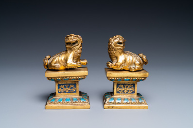 A pair of Chinese gilt bronze Buddhist lions on champlev&eacute; enamel bases, 18/19th C.