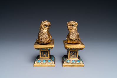 A pair of Chinese gilt bronze Buddhist lions on champlev&eacute; enamel bases, 18/19th C.