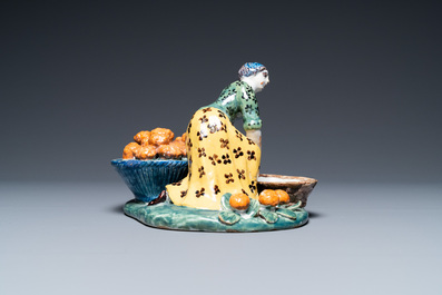 A polychrome Dutch Delft figure of a fruit seller with a small tureen, 18th C.