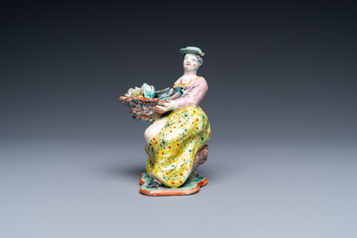 A polychrome Dutch Delft petit feu figure of a bare-breasted flower seller, 18th C.