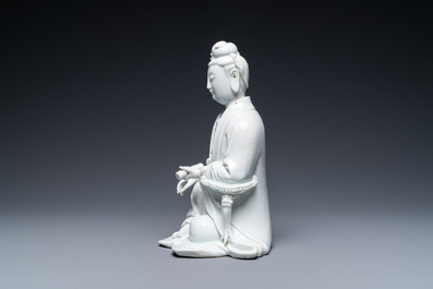 A Chinese Dehua blanc de Chine figure of Guanyin on a wooden stand, 19/20th C.