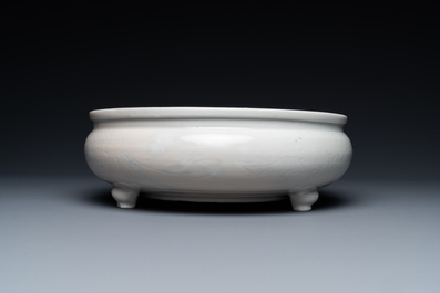 A Chinese Dehua blanc de Chine tripod censer with incised floral design on wooden stand, Kangxi