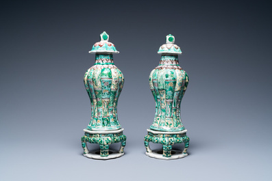 A pair of Chinese verte biscuit vases and covers on stands, Kangxi