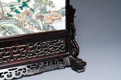 A Chinese rectangular famille rose 'landscape' plaque mounted in a wooden table screen, 19/20th C.