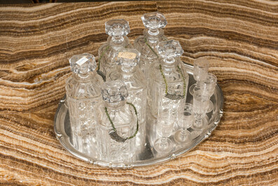 Six faceted glass liquor bottles and five engraved glasses on a silvered tray, 20th C.