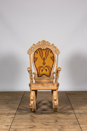 A richly carved wooden rocking chair with snake-shaped legs, 20th C.