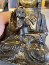 A Chinese partly gilt bronze Guanyin holding a boy, Ming