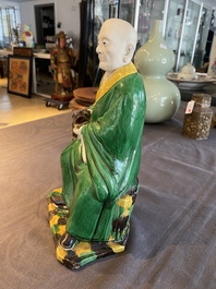 A Chinese verte biscuit figure of a Luohan holding a dog, probably Qing