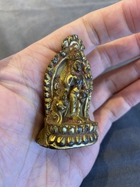 Een vergulde bronzen miniatuur Boeddha met sporen van rode lak, Tibet of Nepal, 15/16 eeuw