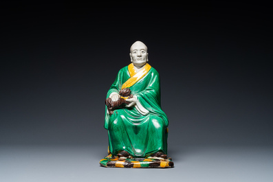 A Chinese verte biscuit figure of a Luohan holding a dog, probably Qing