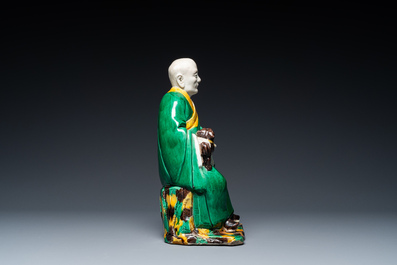 A Chinese verte biscuit figure of a Luohan holding a dog, probably Qing