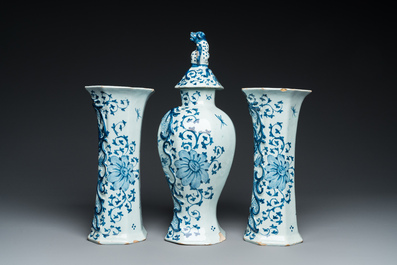 A Dutch Delft blue and white garniture of three vases with a large rose, 18th C.