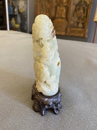 Een Chinese celadon-roest jade sculptuur van een ram op houten sokkel, 19e eeuw