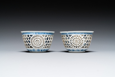 A pair of Chinese blue and white reticulated double-walled cups and saucers, Kangxi