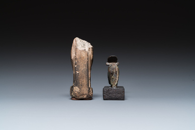 An Egyptian basalt sculpture of a priest or an official holding an Osiris sculpture and a bronze Apis, Late period