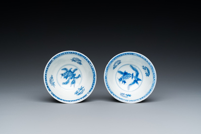 A pair of Chinese blue and white 'carps' cups and saucers, Kangxi