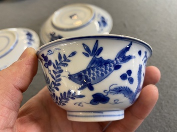 A pair of Chinese blue and white 'carps' cups and saucers, Kangxi