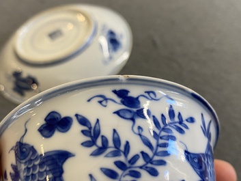 A pair of Chinese blue and white 'carps' cups and saucers, Kangxi