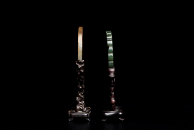 A Chinese celadon and russet jade 'bi' disc and a spinach green flower-shaped pendant on wooden stands, Ming and Qing