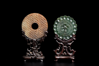 A Chinese celadon and russet jade 'bi' disc and a spinach green flower-shaped pendant on wooden stands, Ming and Qing