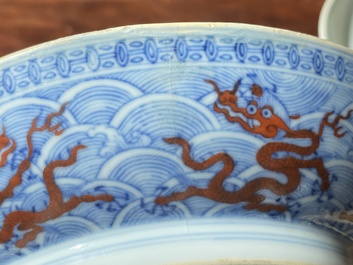 Paire de coupes en porcelaine de Chine &agrave; d&eacute;cor de dragons en rouge de fer sur fond de vagues en bleu et blanc, marque et &eacute;poque de Qianlong