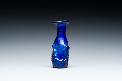 A Roman &lsquo;Sidonian&rsquo; dark blue 'erotic subject' molded glass bottle, Eastern Mediterranean, ca. 1st C.