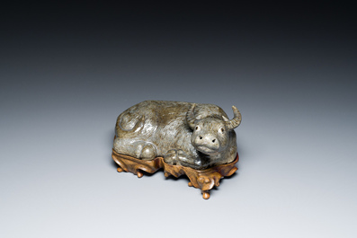 A Chinese monochrome brown-grey-glazed sculpture of a reclining water buffalo on wooden stand, 19th C.