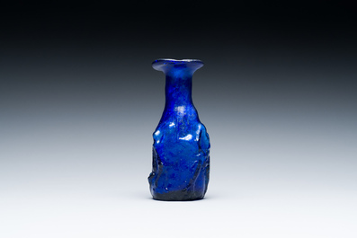 A Roman &lsquo;Sidonian&rsquo; dark blue 'erotic subject' molded glass bottle, Eastern Mediterranean, ca. 1st C.