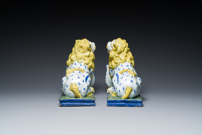 A pair of polychrome French faience lions holding a monogrammed shield, probably Rouen, 18/19th C.