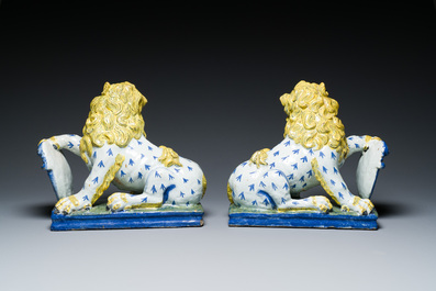 A pair of polychrome French faience lions holding a monogrammed shield, probably Rouen, 18/19th C.