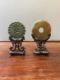 A Chinese celadon and russet jade 'bi' disc and a spinach green flower-shaped pendant on wooden stands, Ming and Qing