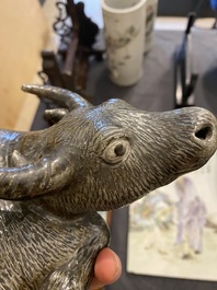 A Chinese monochrome brown-grey-glazed sculpture of a reclining water buffalo on wooden stand, 19th C.